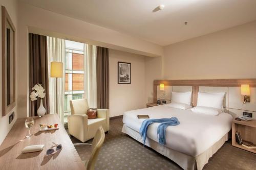 ミラノにあるダブルツリー バイ ヒルトン ミランの大きなベッドとデスクが備わるホテルルームです。