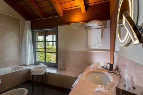 W łazience znajduje się umywalka, wanna i lustro. w obiekcie Grand Hotel Villa Torretta, Curio Collection by Hilton w mieście Sesto San Giovanni