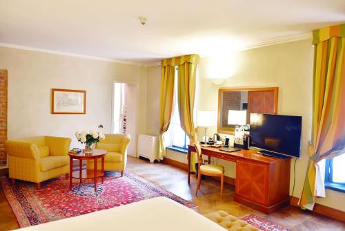 a room with a bed and a desk with a television at Grand Hotel Villa Torretta, Curio Collection by Hilton in Sesto San Giovanni
