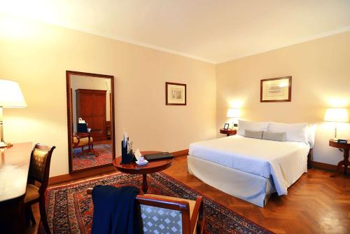 a bedroom with a bed and a table and a mirror at Grand Hotel Villa Torretta, Curio Collection by Hilton in Sesto San Giovanni