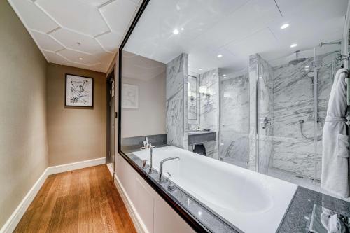 ein großes Bad mit einer Badewanne und einer Dusche in der Unterkunft Chekhoff Hotel Moscow Curio Collection By Hilton in Moskau