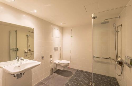 a bathroom with a sink and a toilet and a shower at Hampton By Hilton Munich City West in Munich