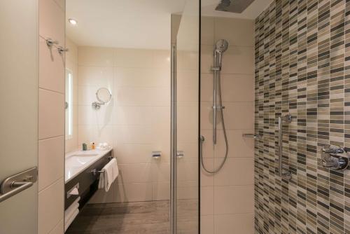 uma casa de banho com um chuveiro e um lavatório. em Hilton Garden Inn Munich City West em Munique
