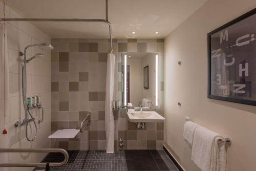 ein Bad mit einem Waschbecken und einer Dusche in der Unterkunft Hampton By Hilton Munich City North in München