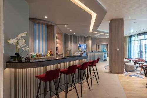a bar with red bar stools in a restaurant at Hampton By Hilton Munich City North in Munich
