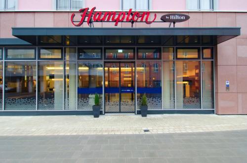 ein Geschäft vor einem Gebäude mit Glastüren in der Unterkunft Hampton by Hilton Nürnberg City Center in Nürnberg