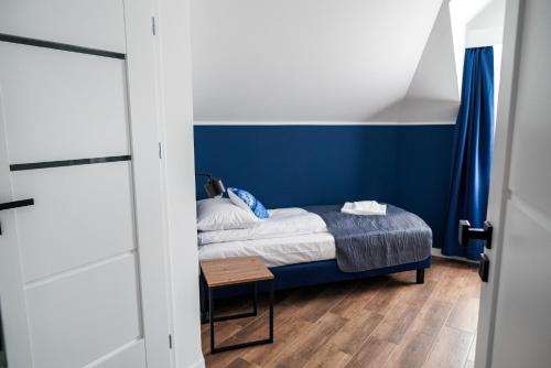 a bedroom with a bed with a blue wall at La Familia TYBURA in Uniejow