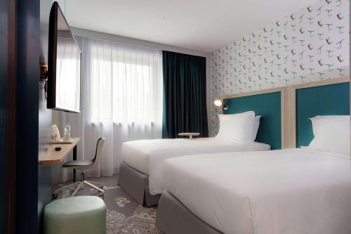 a hotel room with two beds and a desk at Hampton By Hilton Paris Clichy in Clichy