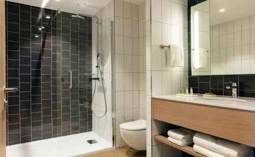 a bathroom with a shower and a toilet and a sink at Hilton Garden Inn Paris Orly Airport in Rungis