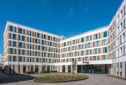 un grand bâtiment de bureau avec une cour en face dans l'établissement Hampton By Hilton Freiburg, à Fribourg-en-Brisgau