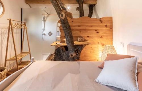 - une chambre avec un lit et un arbre sur le mur dans l'établissement Cabane Dans les Arbres, Domaine de l Ogliastru, à Olmeto