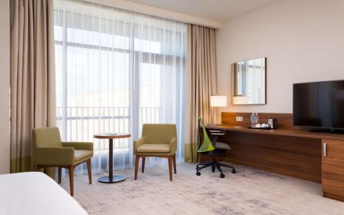 Cette chambre comprend un lit, un bureau et une télévision. dans l'établissement Hilton Garden Inn Orenburg, à Orenbourg