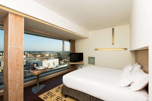 a bedroom with a white bed and a large window at Hilton Garden Inn Rome Claridge in Rome