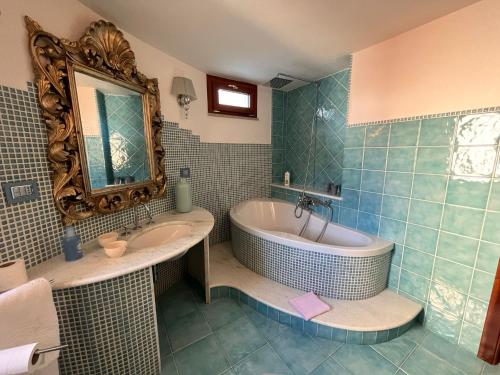 La salle de bains est pourvue d'une baignoire, d'un lavabo et d'un miroir. dans l'établissement B&B Easy Wind, à Cala Gonone