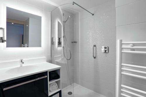 La salle de bains blanche est pourvue d'un lavabo et d'une douche. dans l'établissement Hampton By Hilton Toulouse Airport, à Blagnac