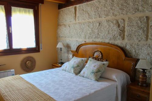 a bedroom with a white bed with two pillows at Casa AsCampinas in Ourense