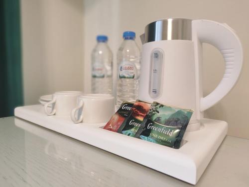 a white coffee pot with cups and water bottles at Crown Hotel in Kutaisi