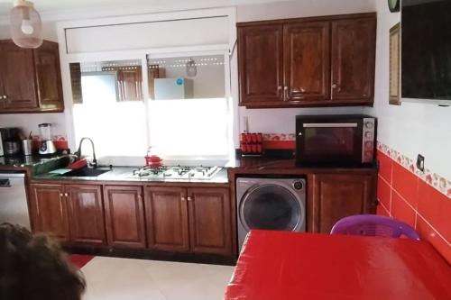 a kitchen with wooden cabinets and a microwave at شقة مفروشة للكراء اليومي في الناظور ليلى in Selouane