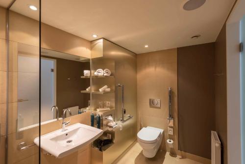 a bathroom with a sink and a toilet and a mirror at Doubletree by Hilton Vienna Schonbrunn in Vienna