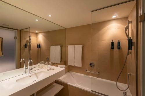 a bathroom with a tub and a sink and a shower at Doubletree by Hilton Vienna Schonbrunn in Vienna