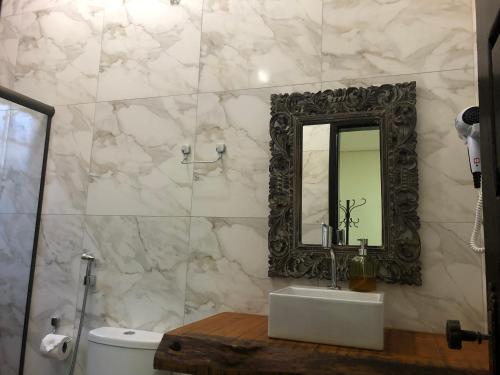 ein Badezimmer mit einem Spiegel, einem Waschbecken und einem WC in der Unterkunft Pousada Vó Iris in Tiradentes