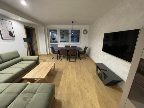 a living room with a couch and a television and a table at Apartamenty Ogrodowa in Ujsoły