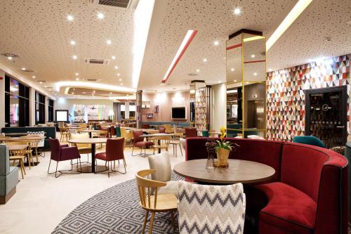 a restaurant with tables and chairs and a red couch at Hampton By Hilton Vienna Messe in Vienna