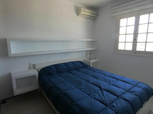 ein blaues Bett in einem weißen Zimmer mit Fenster in der Unterkunft Chalet primera línea, La Barrosa in Chiclana de la Frontera