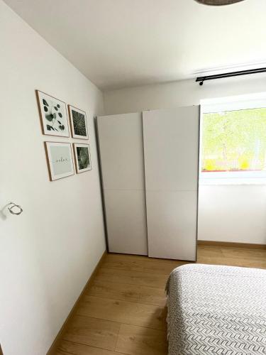 a bedroom with white walls and a bed and a window at Apartamenty Ogrodowa in Ujsoły