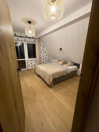 a bedroom with a bed and a window and a chandelier at Apartamenty Ogrodowa in Ujsoły