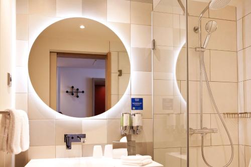 a bathroom with a shower and a sink and a mirror at Hampton By Hilton Vienna Messe in Vienna