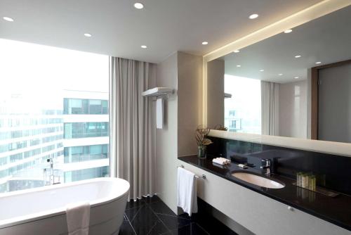 a bathroom with a tub and a sink and a mirror at DoubleTree by Hilton Zagreb in Zagreb