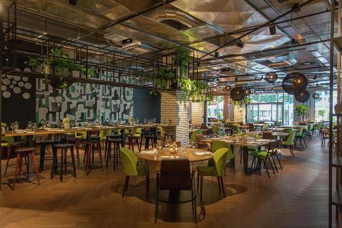 a restaurant with tables and chairs and plants at Hilton Garden Inn Zagreb - Radnička in Zagreb