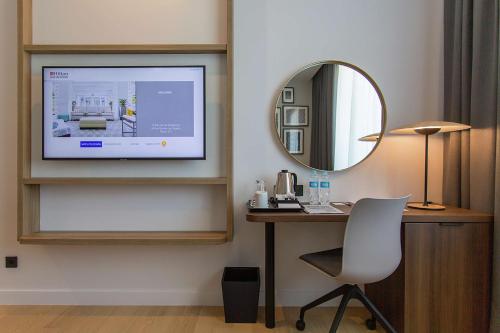 a room with a desk and a television on a wall at Hilton Garden Inn Zagreb - Radnička in Zagreb