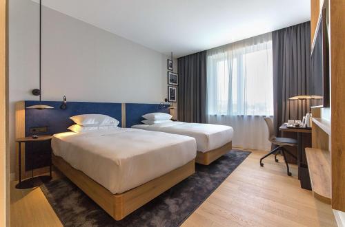 a hotel room with two beds and a desk at Hilton Garden Inn Zagreb - Radnička in Zagreb