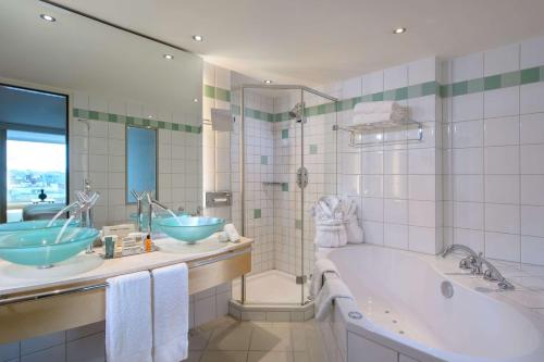 a bathroom with two sinks and a bath tub at Hilton Zurich Airport in Opfikon