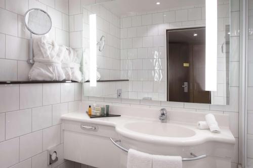 a white bathroom with a sink and a mirror at Hilton Zurich Airport in Opfikon