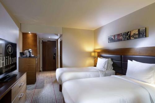 a hotel room with two beds and a television at Hilton Zurich Airport in Opfikon