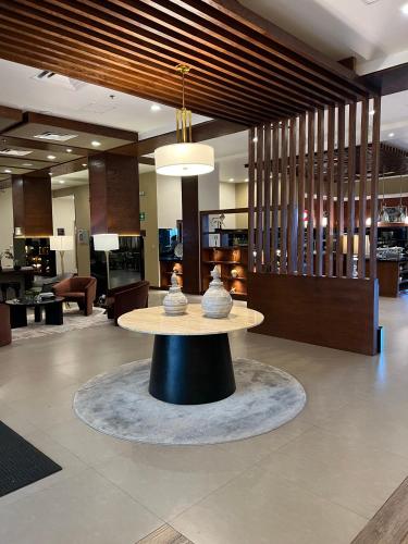 a lobby with a table in the middle of a room at Best Western Plus Chihuahua Juventud in Chihuahua
