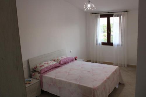 a bedroom with a bed with pink sheets and a window at Casa Bel Panorama in Orosei