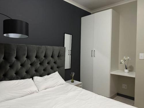 a bedroom with a large white bed with a black headboard at Hidden gem with gorgeous sunsets - One on Heather in Midrand