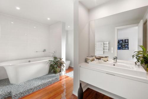 a white bathroom with a tub and a sink at Linger Lakeside in Taupo