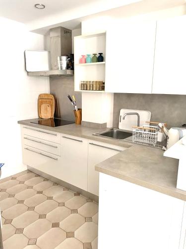 une cuisine avec des armoires blanches et un sol carrelé dans l'établissement Appartement 3P 88 m2 terrasse et jardin à 20 metres de la plage, à Antibes