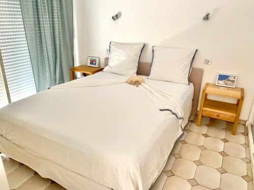 um quarto com uma grande cama branca e duas mesas em Appartement 3P 88 m2 terrasse et jardin à 20 metres de la plage em Antibes