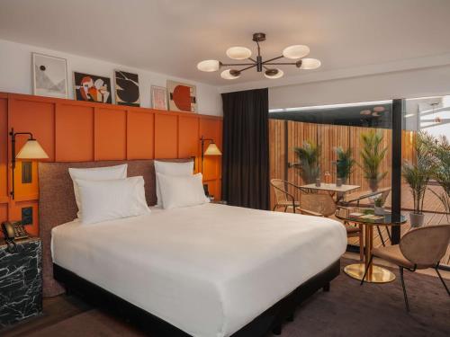 Un dormitorio con una gran cama blanca y una mesa en Marty Hotel Bordeaux - Tapestry Collection by Hilton, en Burdeos