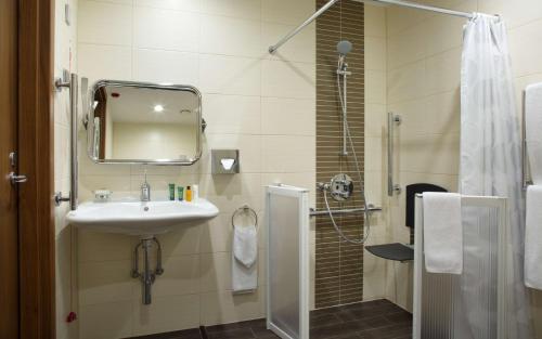 een badkamer met een wastafel en een douche met een spiegel bij Hilton Garden Inn Ufa Riverside in Oefa