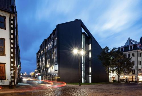 a black building on a city street at night at Hilton Garden Inn Riga Old Town in Rīga