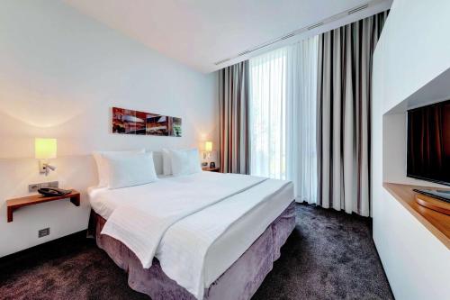 a hotel room with a large bed and a television at Hilton Garden Inn Stuttgart NeckarPark in Stuttgart