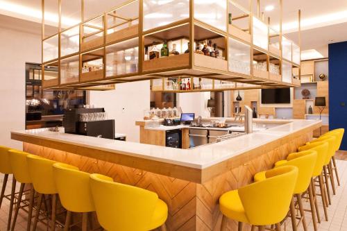 a bar with yellow chairs at a restaurant at Hilton Garden Inn Munich Messe in Feldkirchen