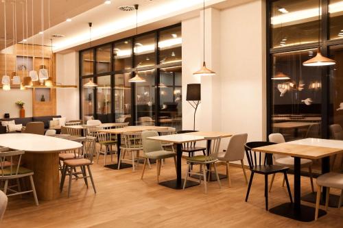a restaurant with tables and chairs and windows at Hilton Garden Inn Munich Messe in Feldkirchen